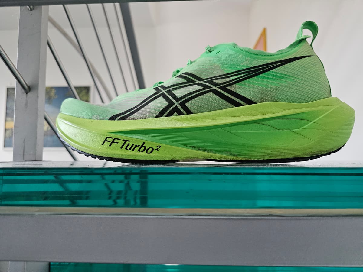 La ASICS Megablast appoggiata di profilo su un piano di vetro: la punta resta sollevata